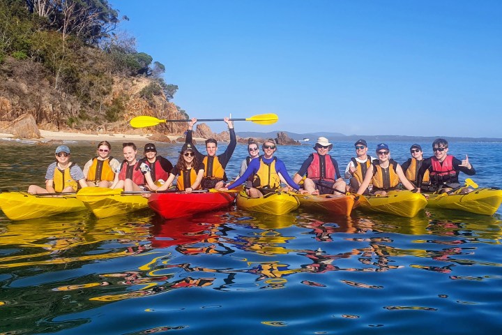 a group of people riding on the back of a boat in the water